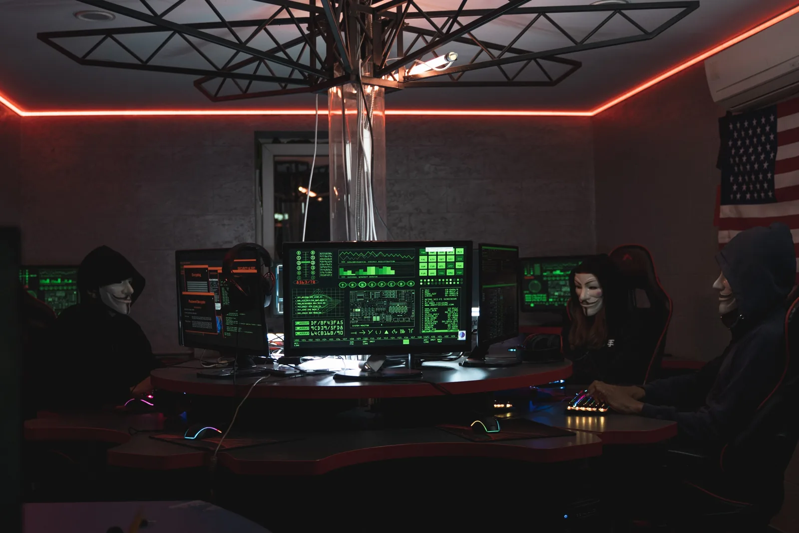 salle de reunion sombre avec des personnes portant le maque des anonymous autour de la table